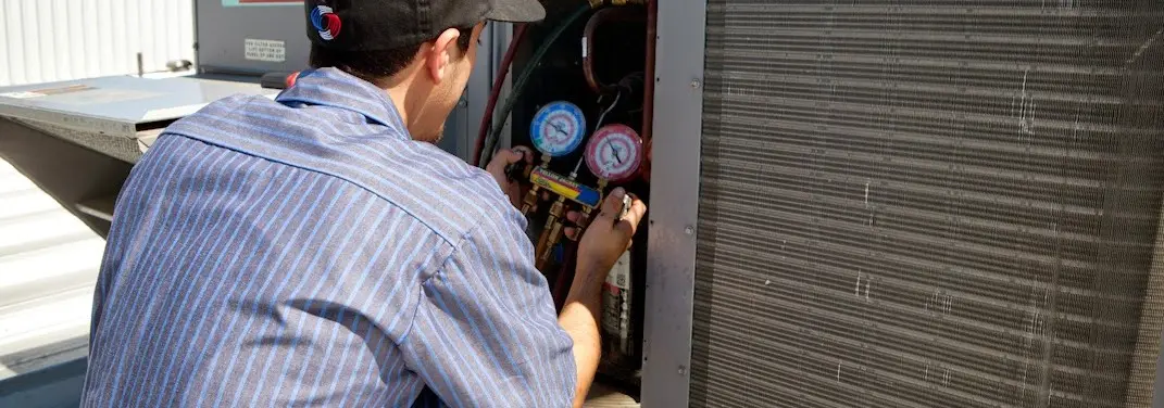 HVAC technician servicing a condenser unit in Linden