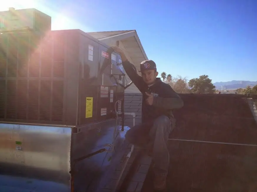 HVAC technician performing Air Duct Cleaning on a rooftop unit in Linden
